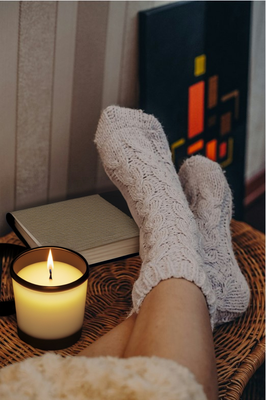 feet in cozy socks on a table, naked legs, candle, notebook, comfy. used socks.