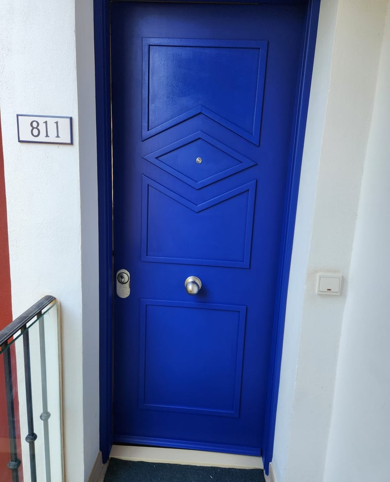 Modern vibrant blue apartment front door with geometric panels and house number 811.