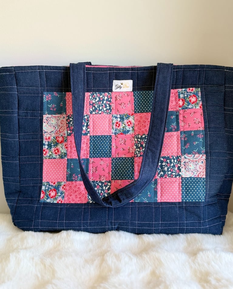 Handmade quilted denim tote bag featuring a pink and blue floral patchwork panel design.