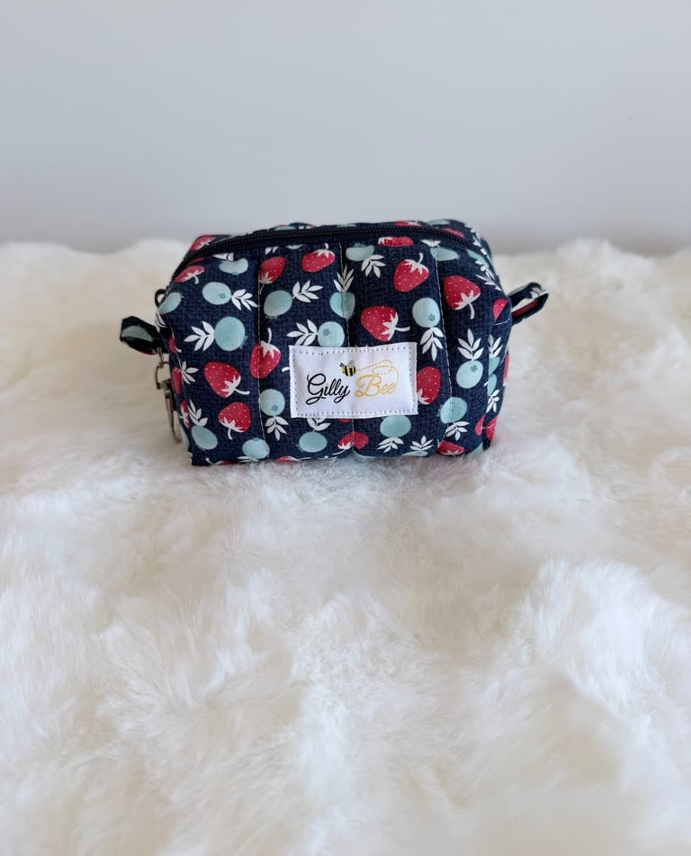 Handmade strawberry print keychain pouch with zipper on white faux fur.