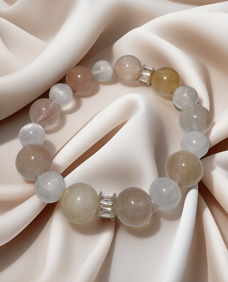 Elegant natural quartz gemstone bracelet with neutral round beads on draped silk fabric.