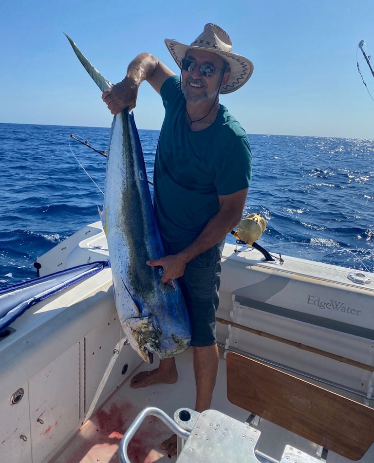 Un client souriant tenant une dorade coryphène dans les mains