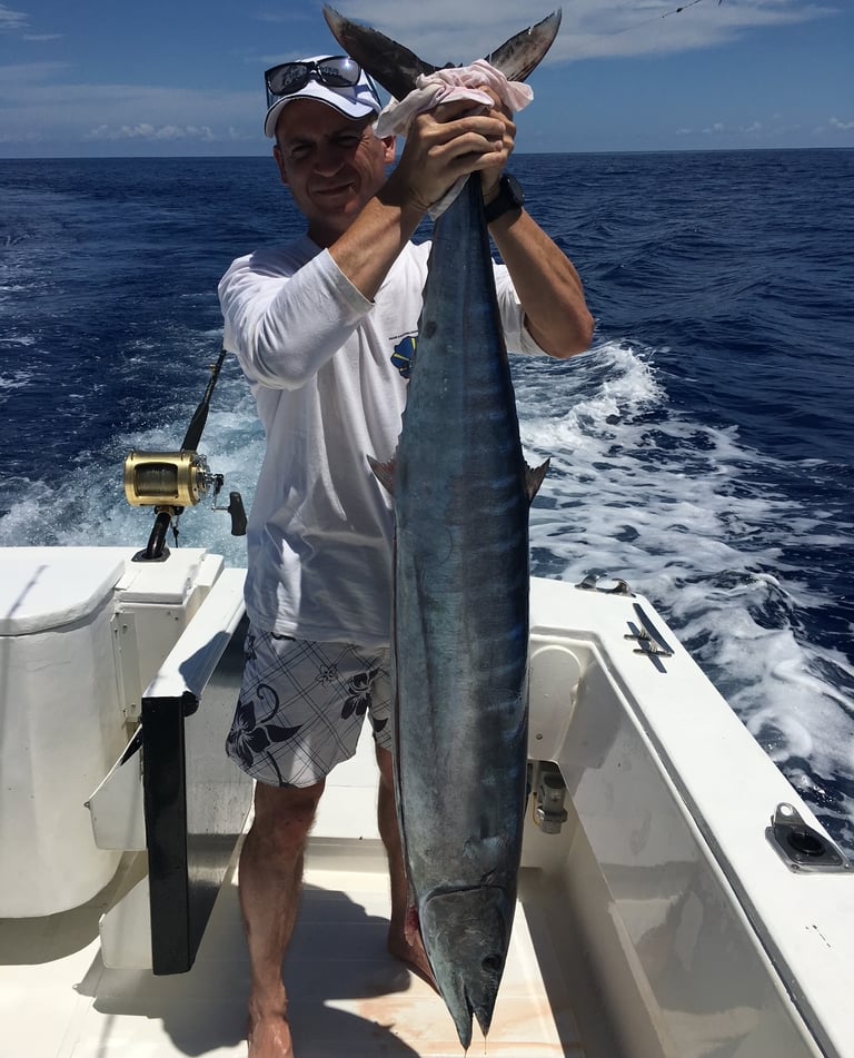 Un client tenant un thon banane par la queue sur le bateau