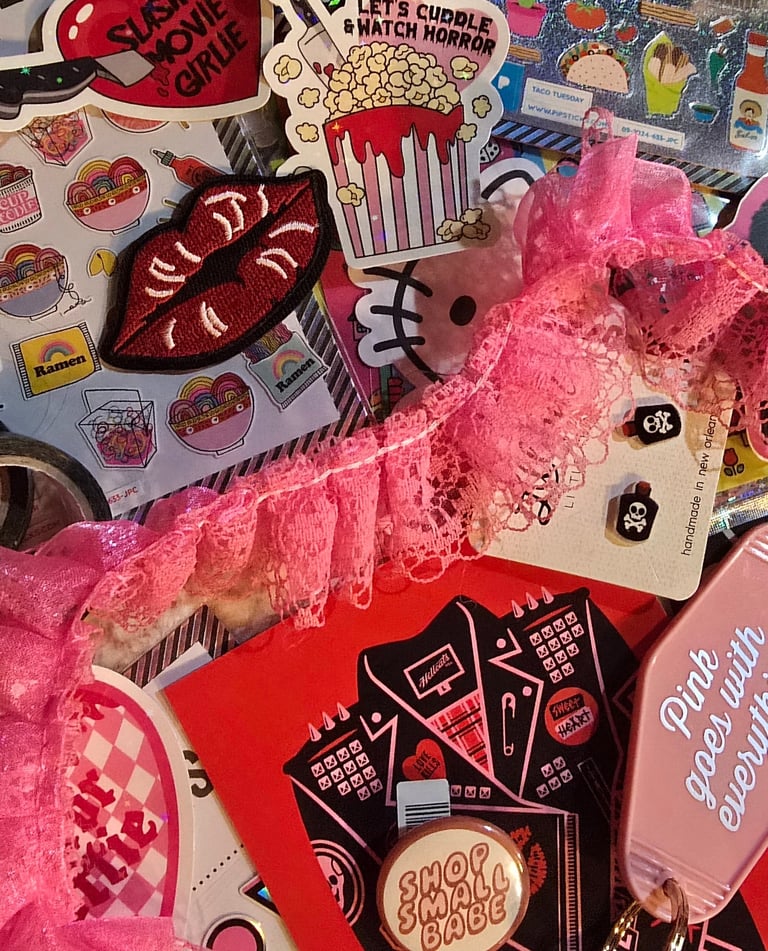 piles of earrings, stickers, patches, postcards and snippets of hot pink lace