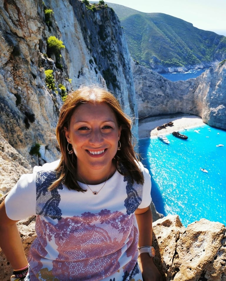 a woman standing on a cliff overlooking a cliff and beach