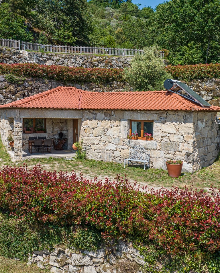 a small stone house with a red roof and a red roof