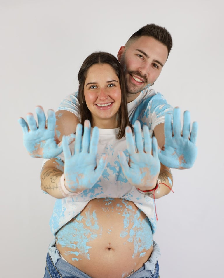 Sessió de fotos de gender reveal a Girona d'una parella amb pintura blava en estudi fotogràfic