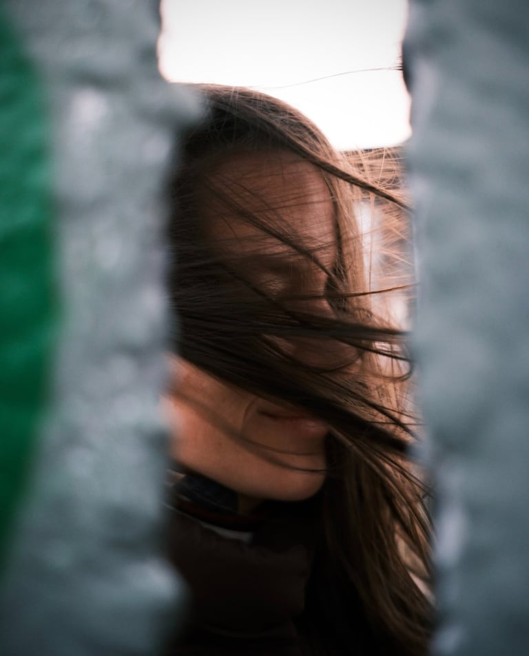 a woman with long hair and a black jacket. wind is blowing in the hair.
