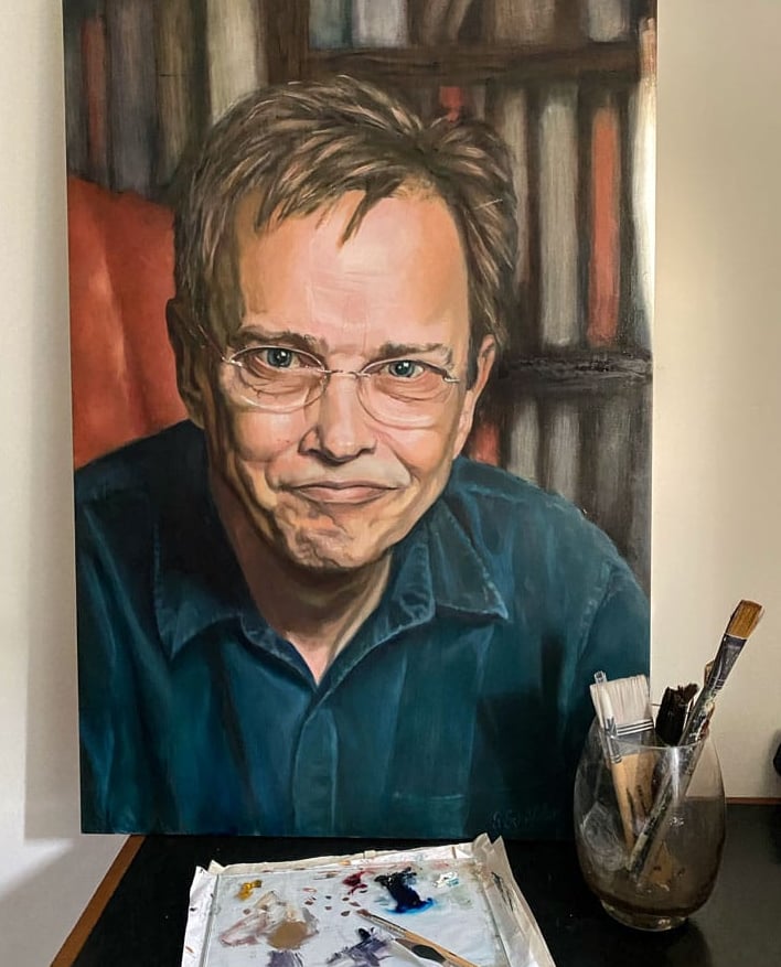Oil painting and brushes of man with glasses by bookshelf.