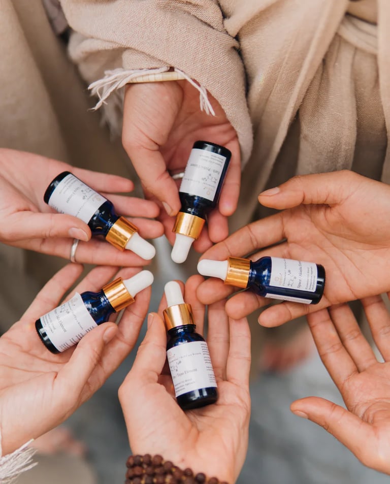 Diverse hands holding organic blue glass dropper bottles with essential oil blends and herbal serums.