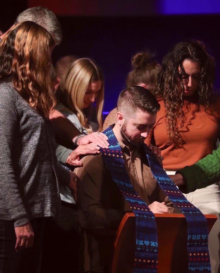 Cole bowed in prayer during what appears to be an ordination or commissioning ceremony.