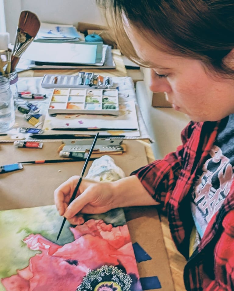 Artist painting a vibrant pink watercolor floral painting  in a home art studio setup.