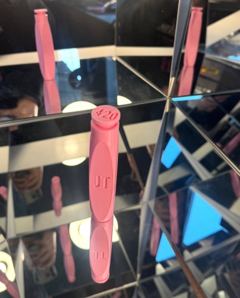 Pink 420 branded cannabis accessory standing on a mirrored surface with multiple reflections.