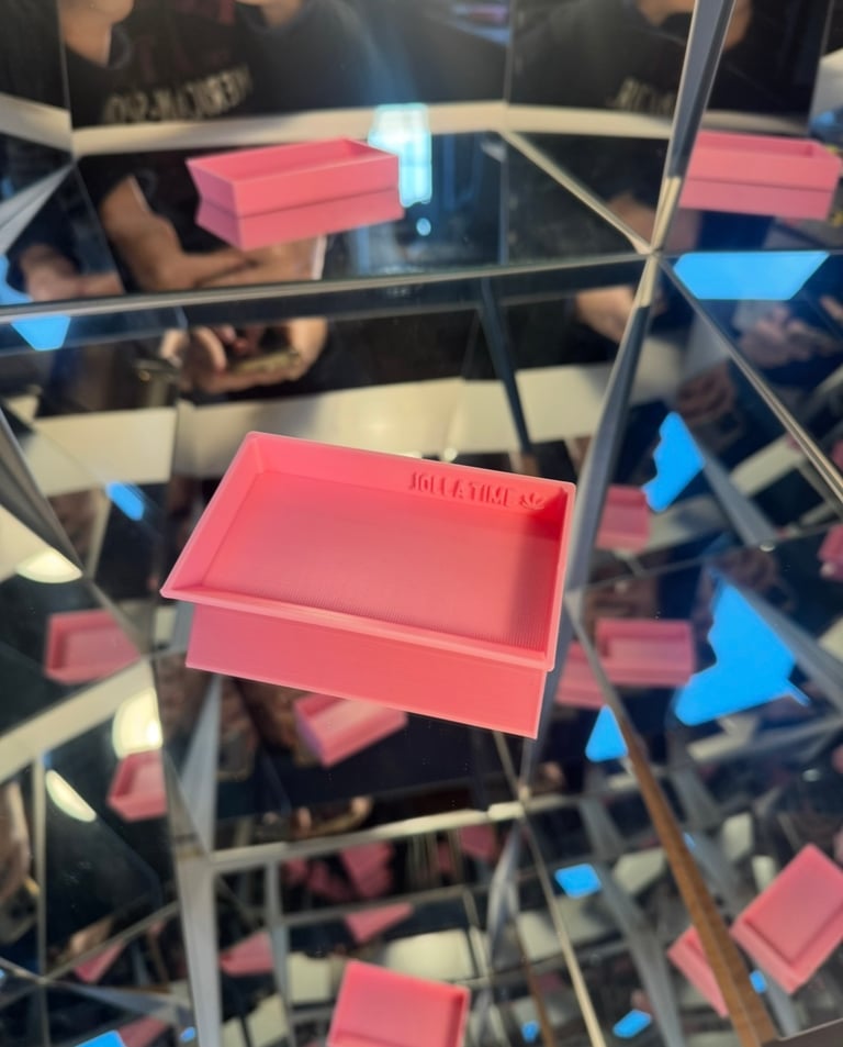 Pink 3D printed rolling tray with Roll A Time logo inside a reflective mirror kaleidoscope box.