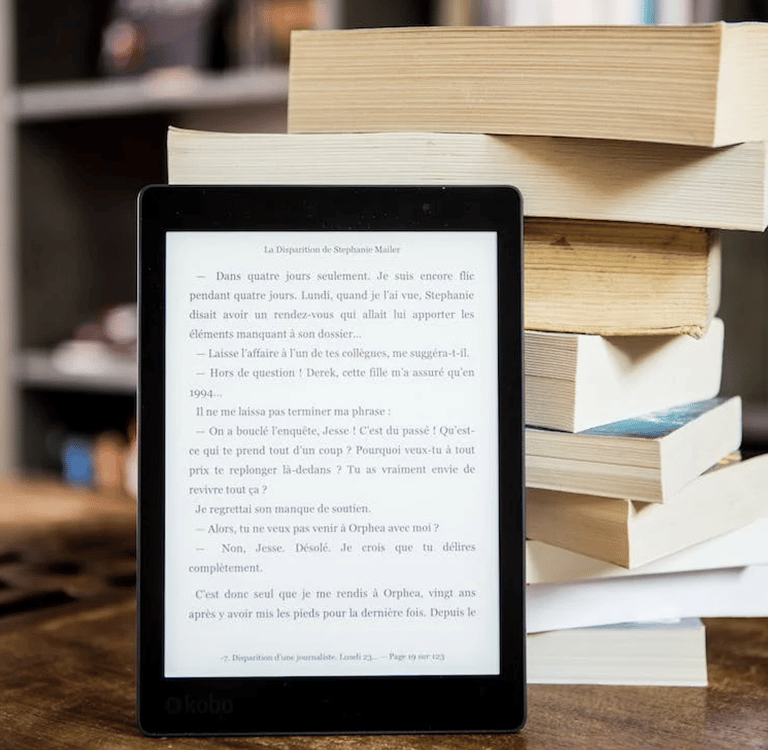 a tablet computer sitting on a table with a stack of books