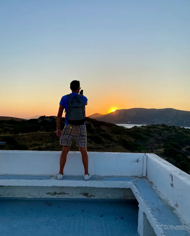 a man with a camera taking shots on sunset on white balcony