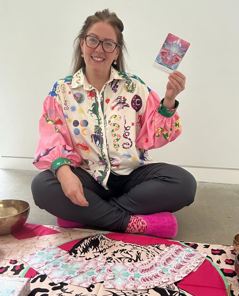 photo of gabi smiling at the camera holding an oracle card
