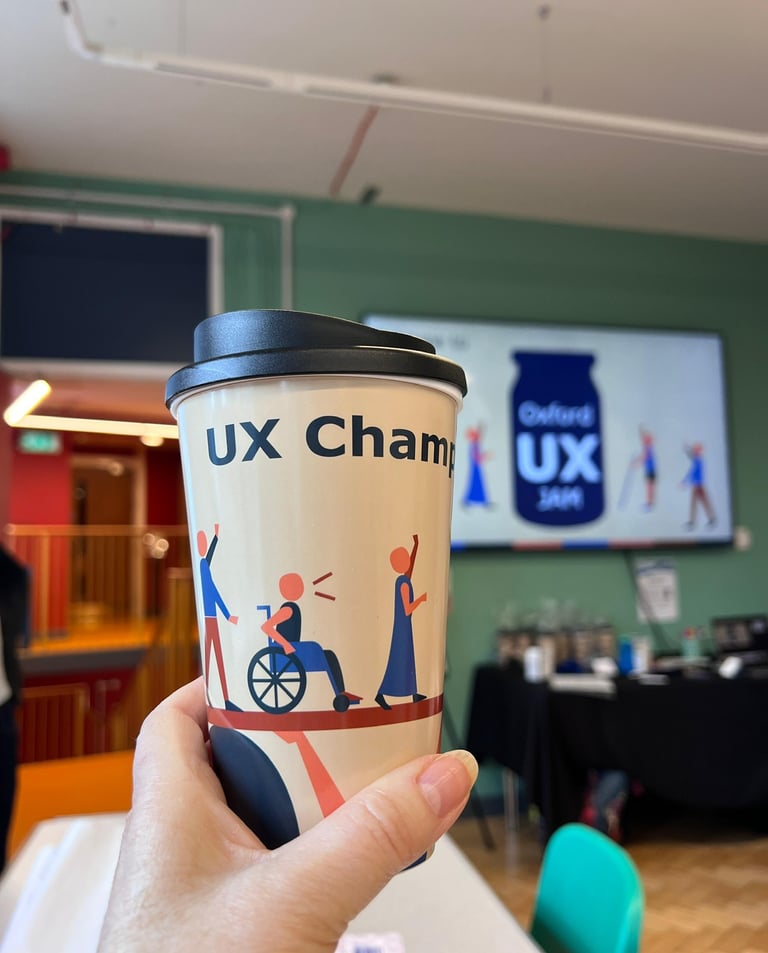 A reusable coffee cup featuring inclusive UX design illustrations at an Oxford UX Jam workshop event.