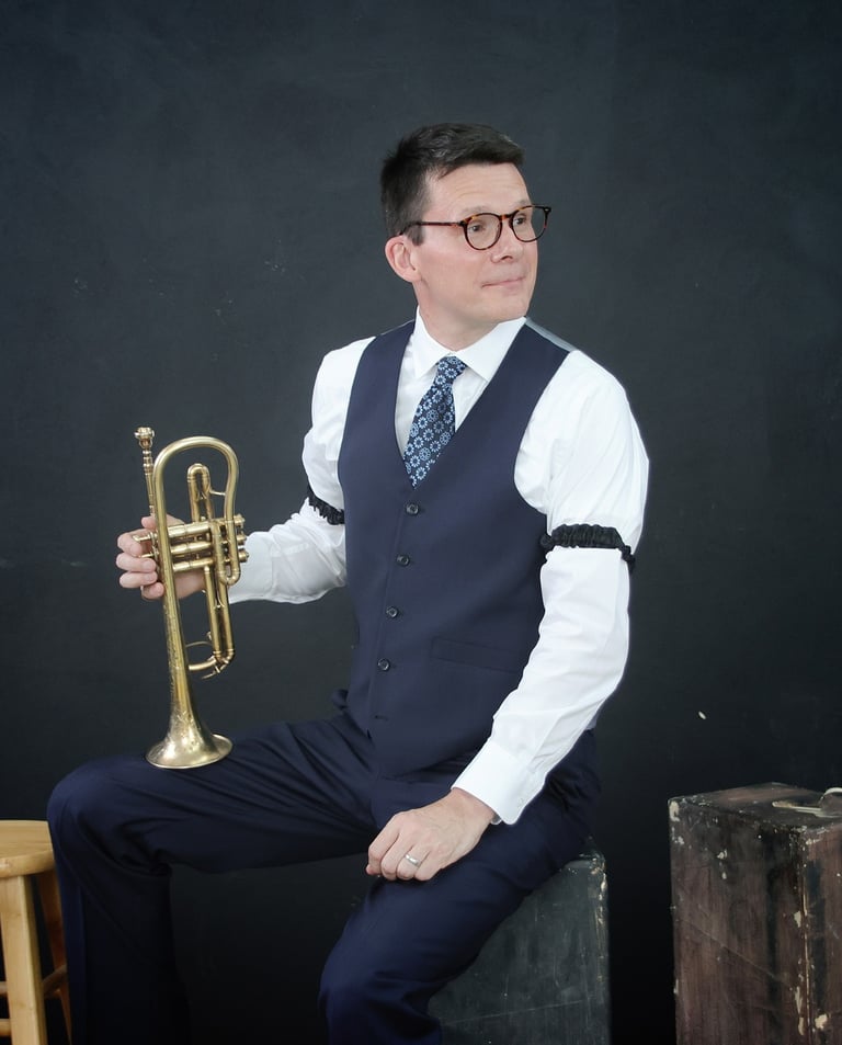 A man in a vest and tie is holding a cornet, looking to the side.
