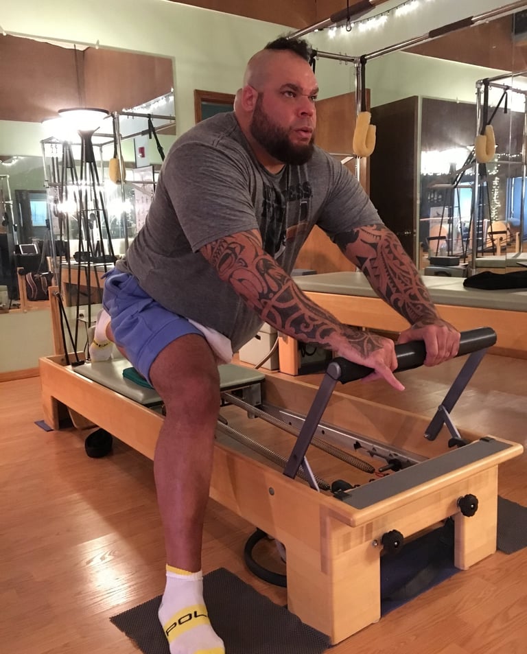 one man on a pilates reformer doing a stretch