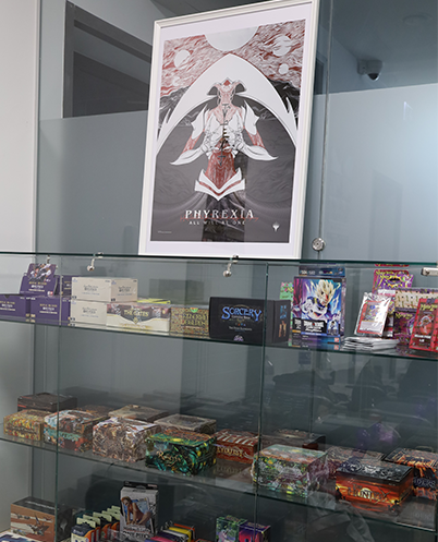 A display of TCG boxes, containing Flesh and Blood, One Piece TCG and more products.