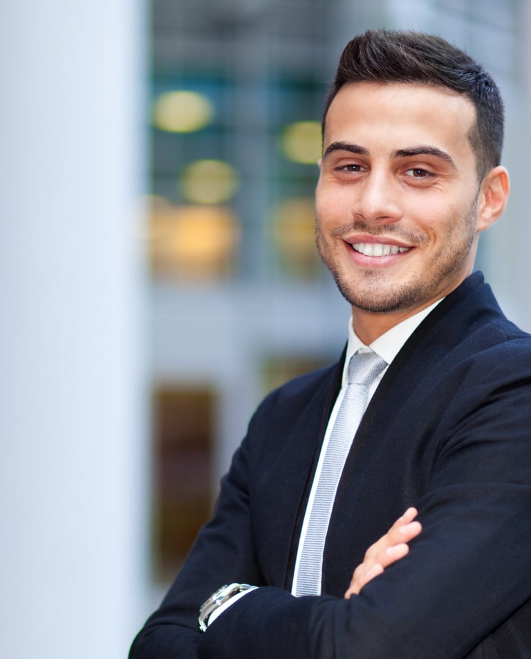young man in suit smiling in front of an office building