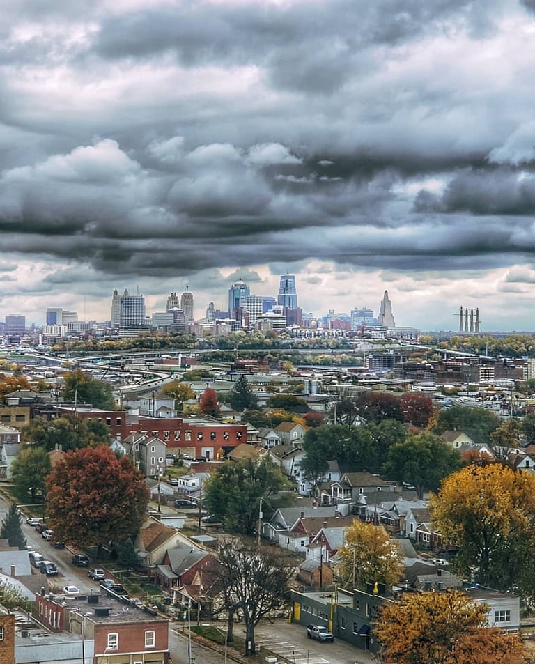 Downtown Kansas City, Missouri landscape photo taken during the fall with vibrant trees and deep, cloudy skies.