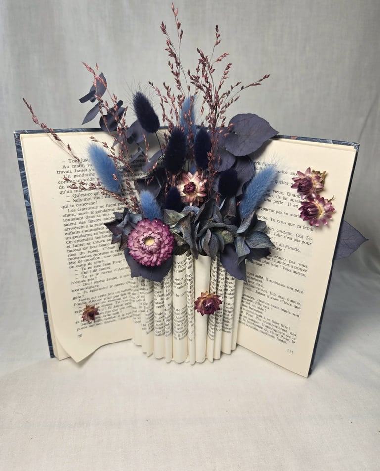 Livre ouvert avec fleurs séchées tons bleu et mauve, crée par l'Ensorce'Fleurs
