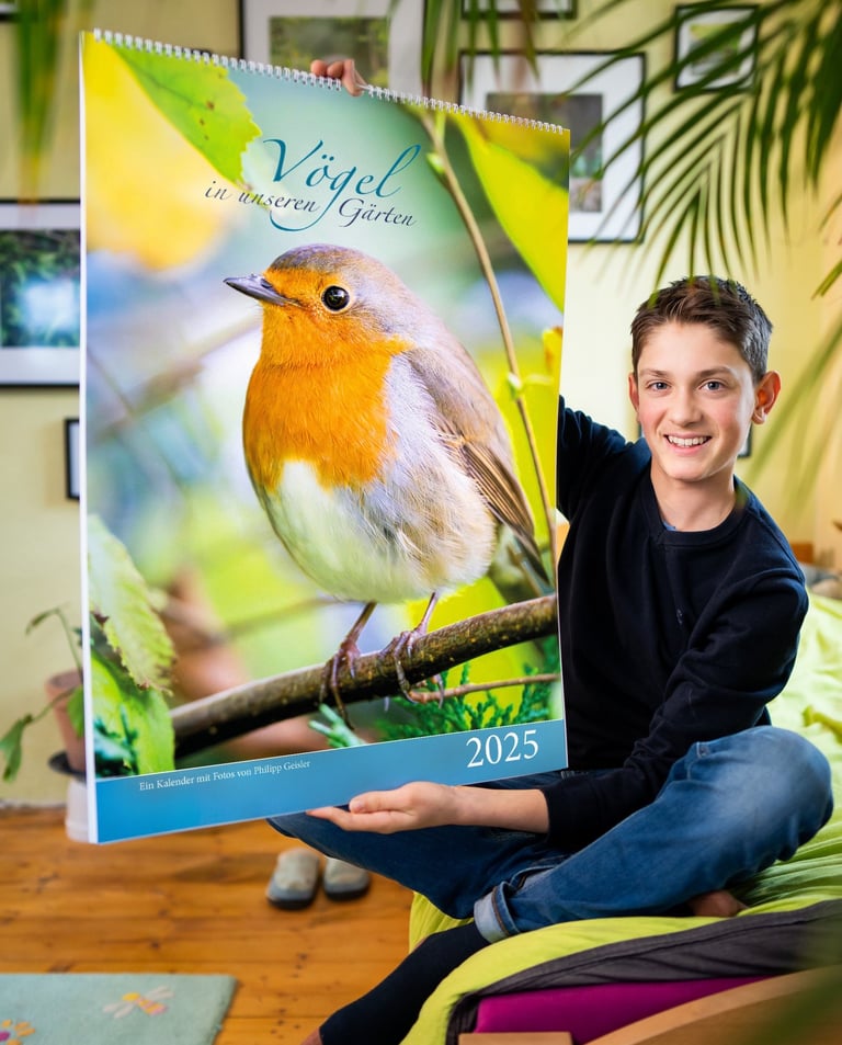 Philipp Geisler präsentiert seinen großen Fotokalender mit Vogelmotiven in seinem Zimmer