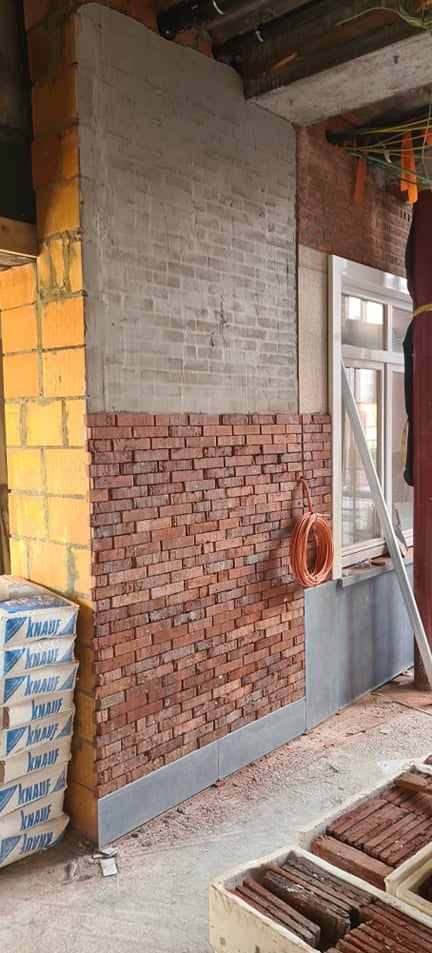 Rénovation de façade intérieure avec isolation thermique, parement en briques rouges et mur en béton