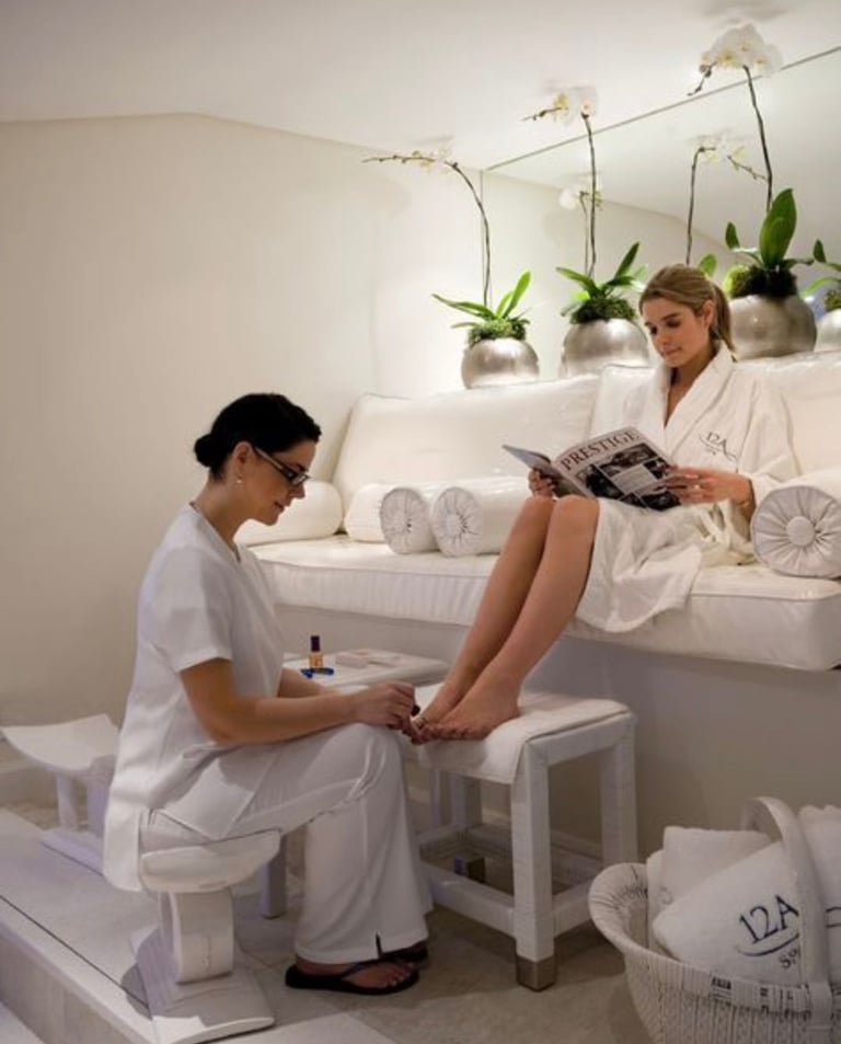 A woman in a white robe enjoys a professional pedicure treatment at a luxury spa.