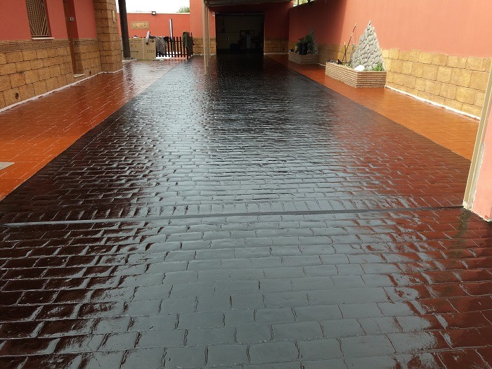 Superficie de hormigón decorativo con acabado de resina y pintura en tonos oscuros, ideal para entradas y patios.