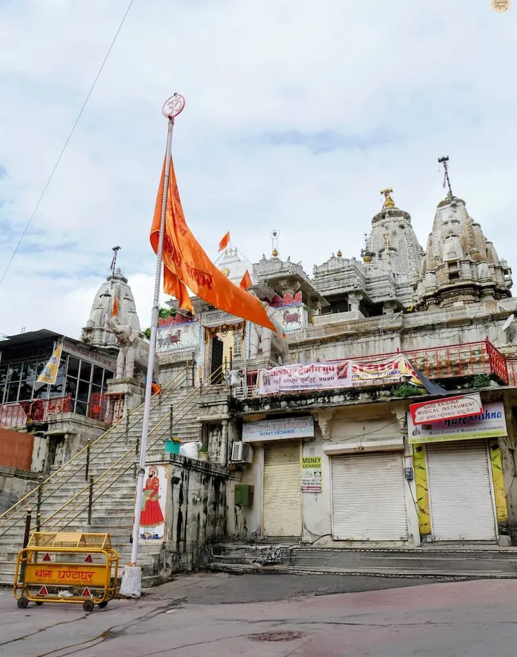 Street view of Jagdish Temple in Udaipur, showing bustling old-city lanes leading to the tall, carved shikhara.