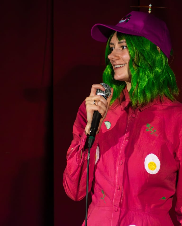 Moira Adomaite performing in a stand up show dressed like pink soup
