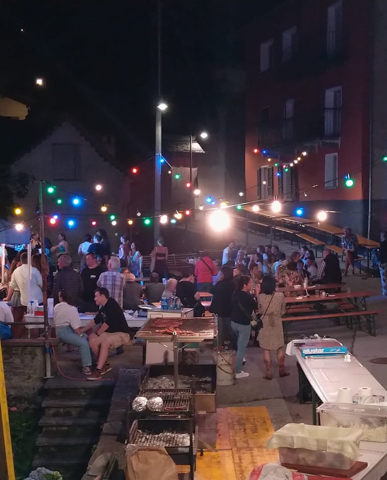 a group of people sitting at tables with lights on, festa campestre Menzonio