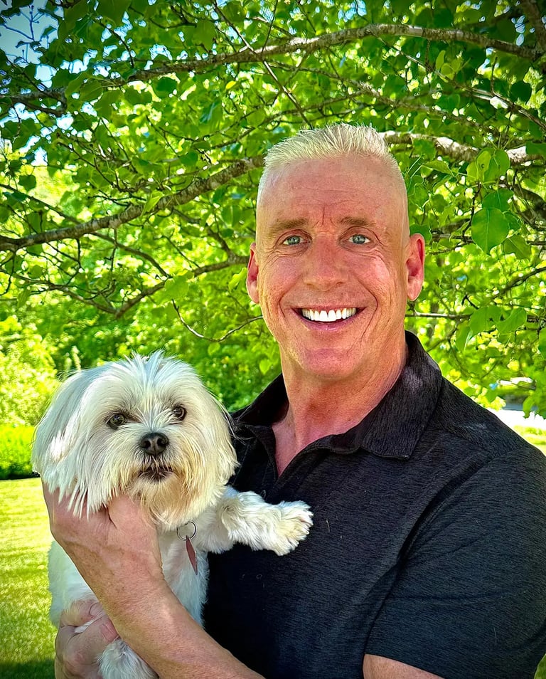 a man in a black shirt is holding a white dog, Tom O'Brien, Owner, Tymeless Properties