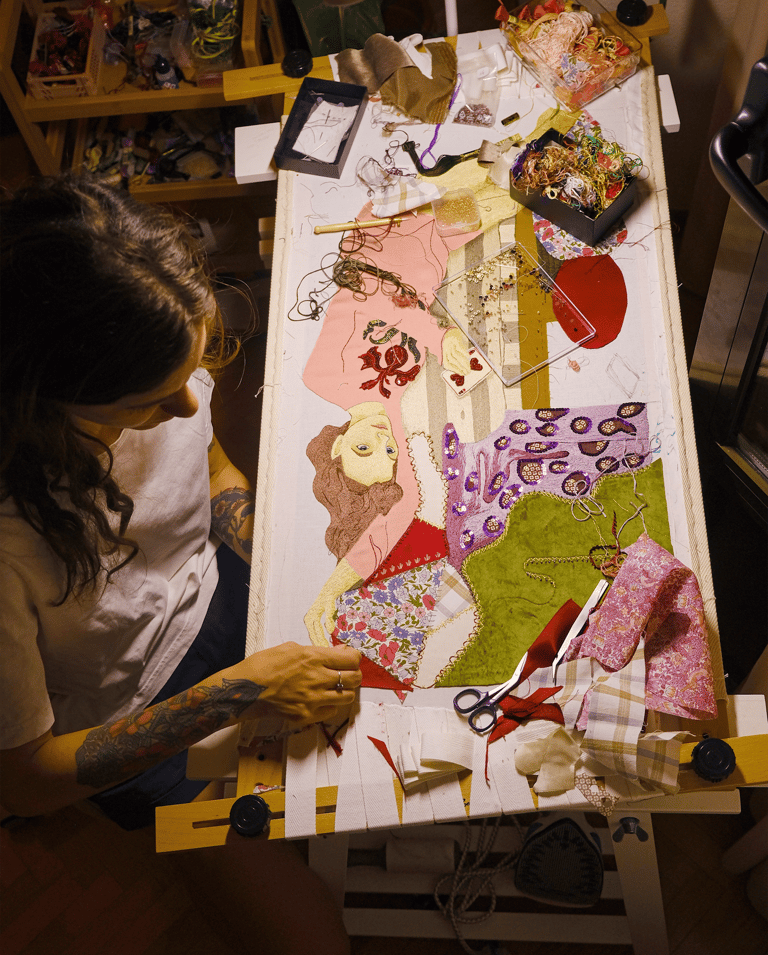 a woman is sitting at a table with a large piece of art work