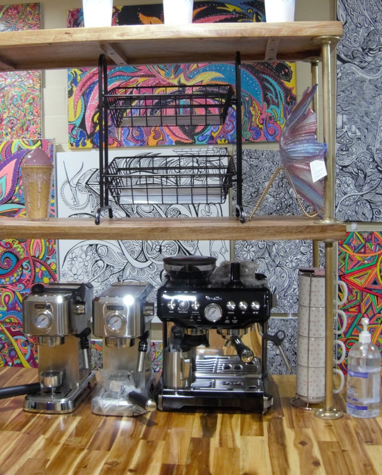 Coffee machines behind customer counter, with artwork by Chef Nick on wall behind them.