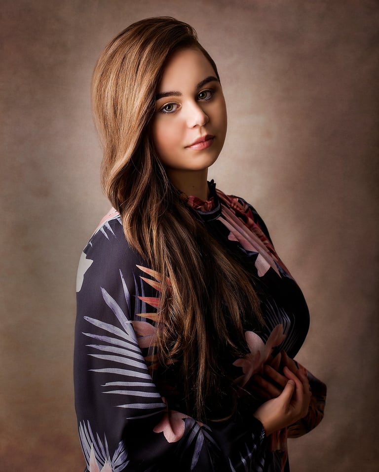 a beautiful girl posing in a photography studio, she has long light brown wavey hair and green eyes