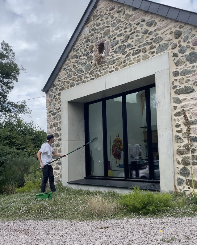 Nettoyage de grandes baies vitrées en cours avec mouilleur et raclette pour un résultat sans traces.