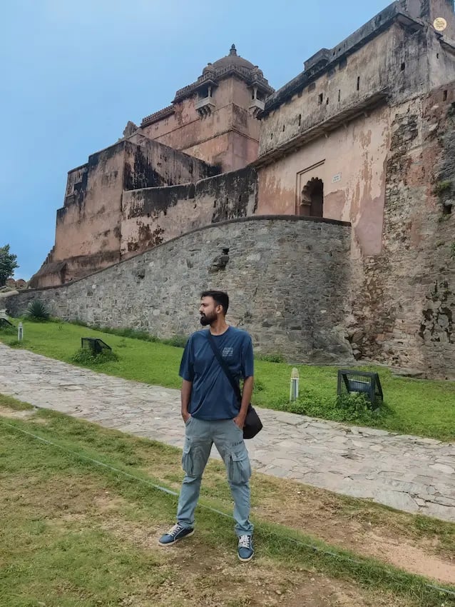Traveler posing against the massive stone walls of Kumbhalgarh Fort in Rajasthan.