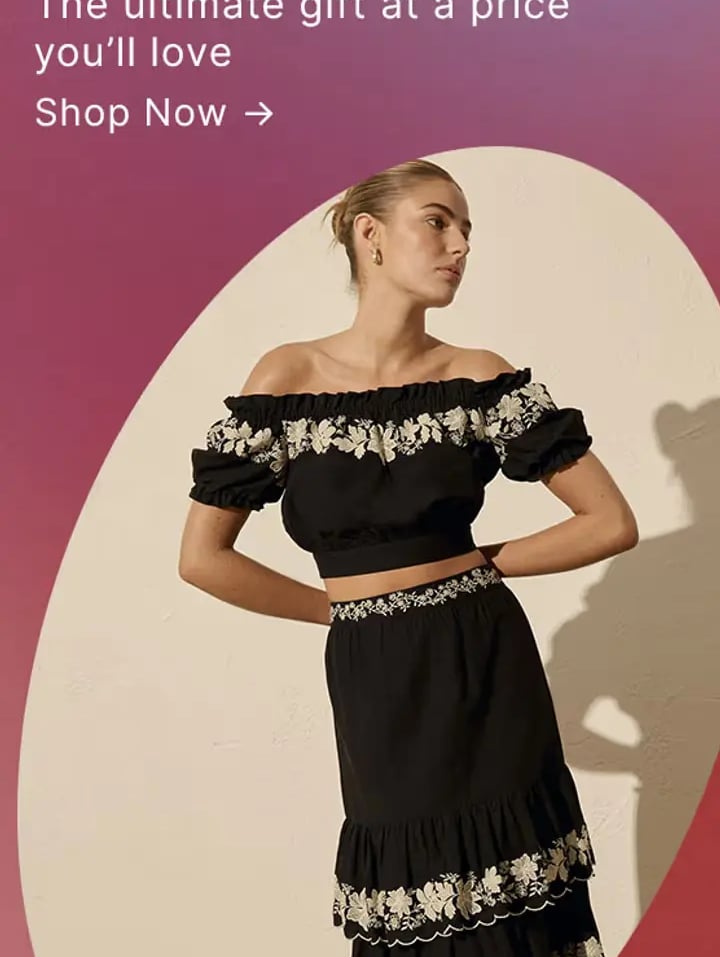 Woman wearing a Forever New black off-the-shoulder crop top and matching tiered floral embroidered skirt.