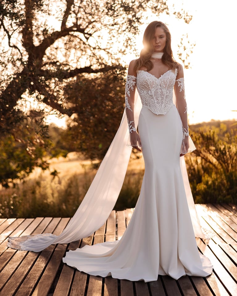 Elegant mermaid wedding dress with a lace corset bodice and long sleeves for an outdoor sunset ceremony.