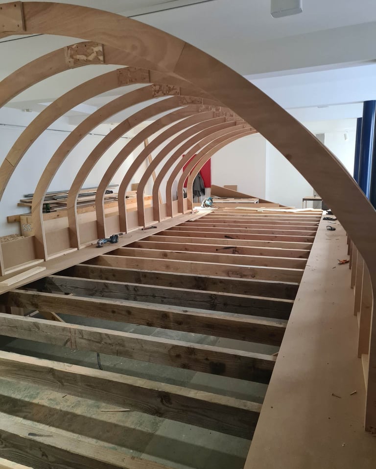 Construction d’une ossature bois avec arches cintrées – structure sur mesure pour charpente intérieu