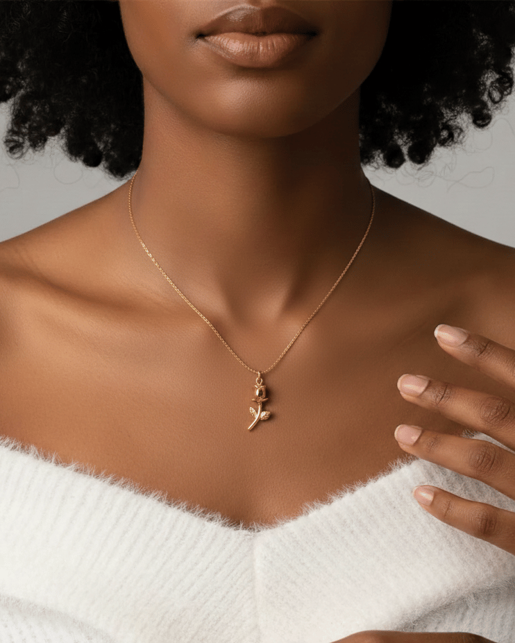 Elegant gold rose pendant necklace worn by a woman in a white sweater.