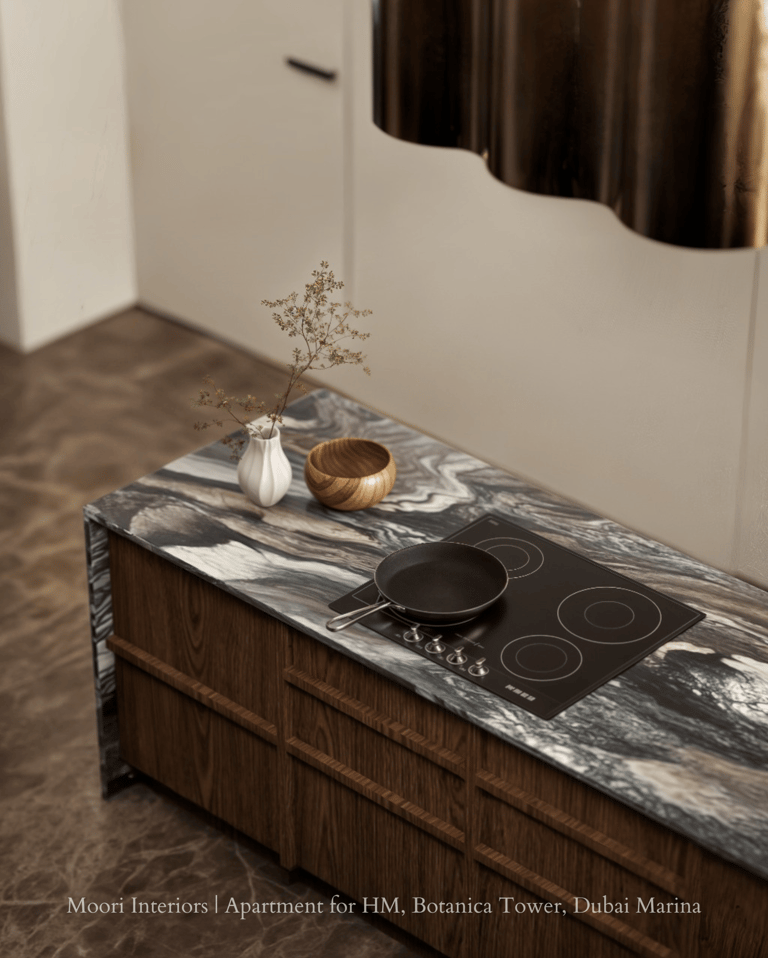 Black induction hob set into a patterned marble kitchen island with wooden cabinetry.