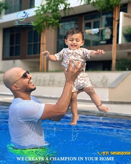 Smiling coach holding up his student during a fun swimming lesson in an outdoor pool.