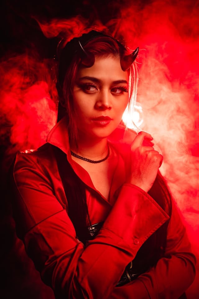 a woman in a devilish costume holding a cigarette