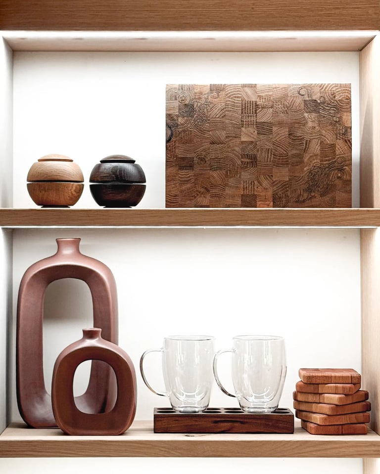 Styled wooden shelving featuring an end-grain chopping board, ceramic vases, glass mugs and coasters