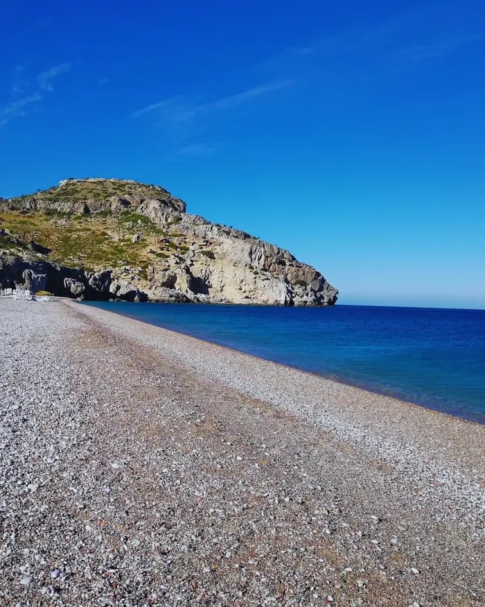a beach with a rocky beach and a blue sky